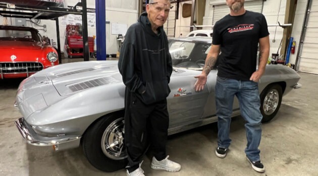 Two men are standing beside a second-generation Corvette coupe.