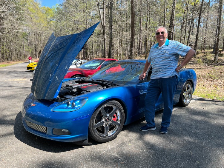 A man standing beside a blue Corvette