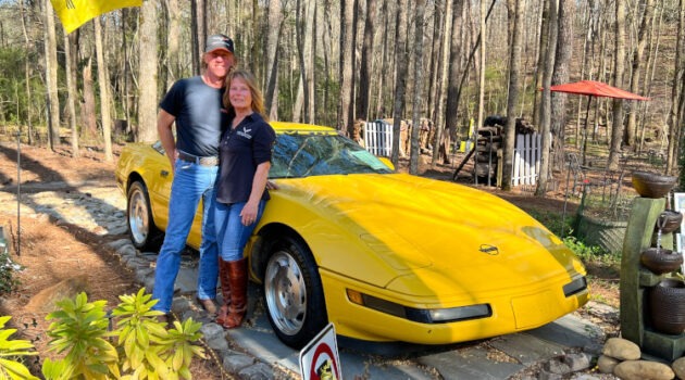 Two people standing beside a yellow C4 Corvette