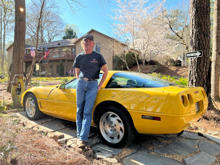 A yellow C4 Corvette parked in the woods. 