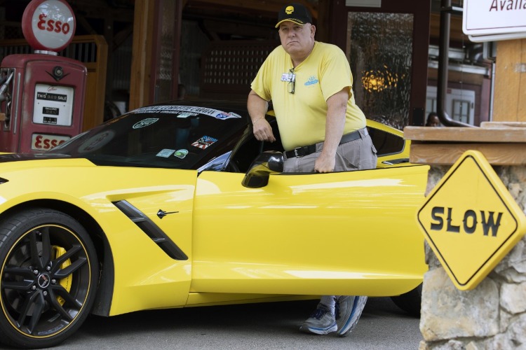 A man standing beside a yellow Corvette