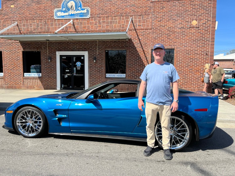 A man is standing beside a blue ZR1 Corvette